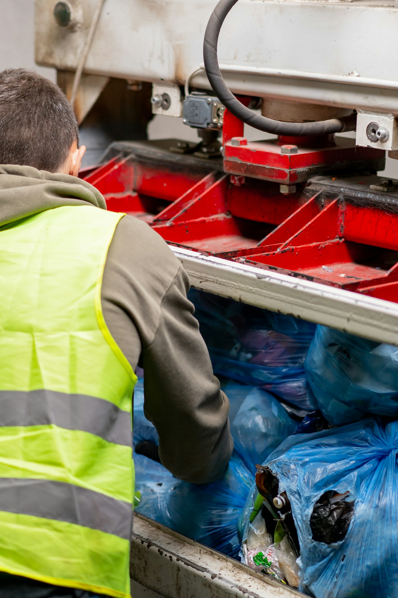 a recycling plant employee putting bags of garbage into special press machine for waste disposal